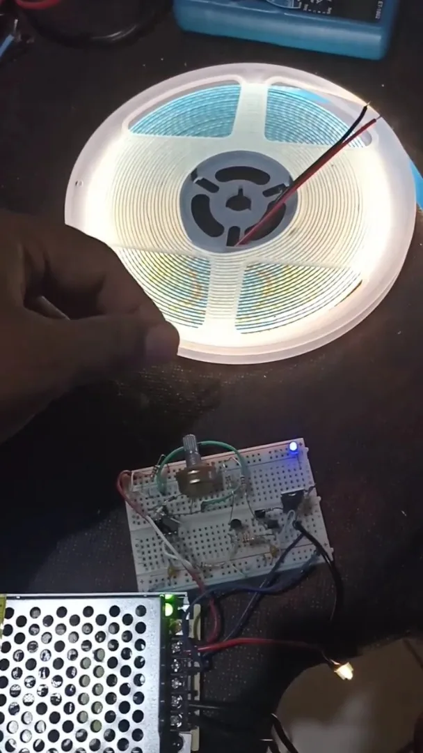 Fita de LED, protoboard com temporizador 555 e fonte durante o teste de PWM
