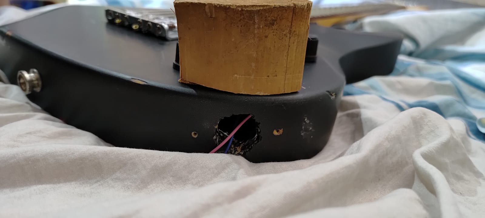 Lateral da guitarra com a abertura do jack e fios expostos durante a modificação