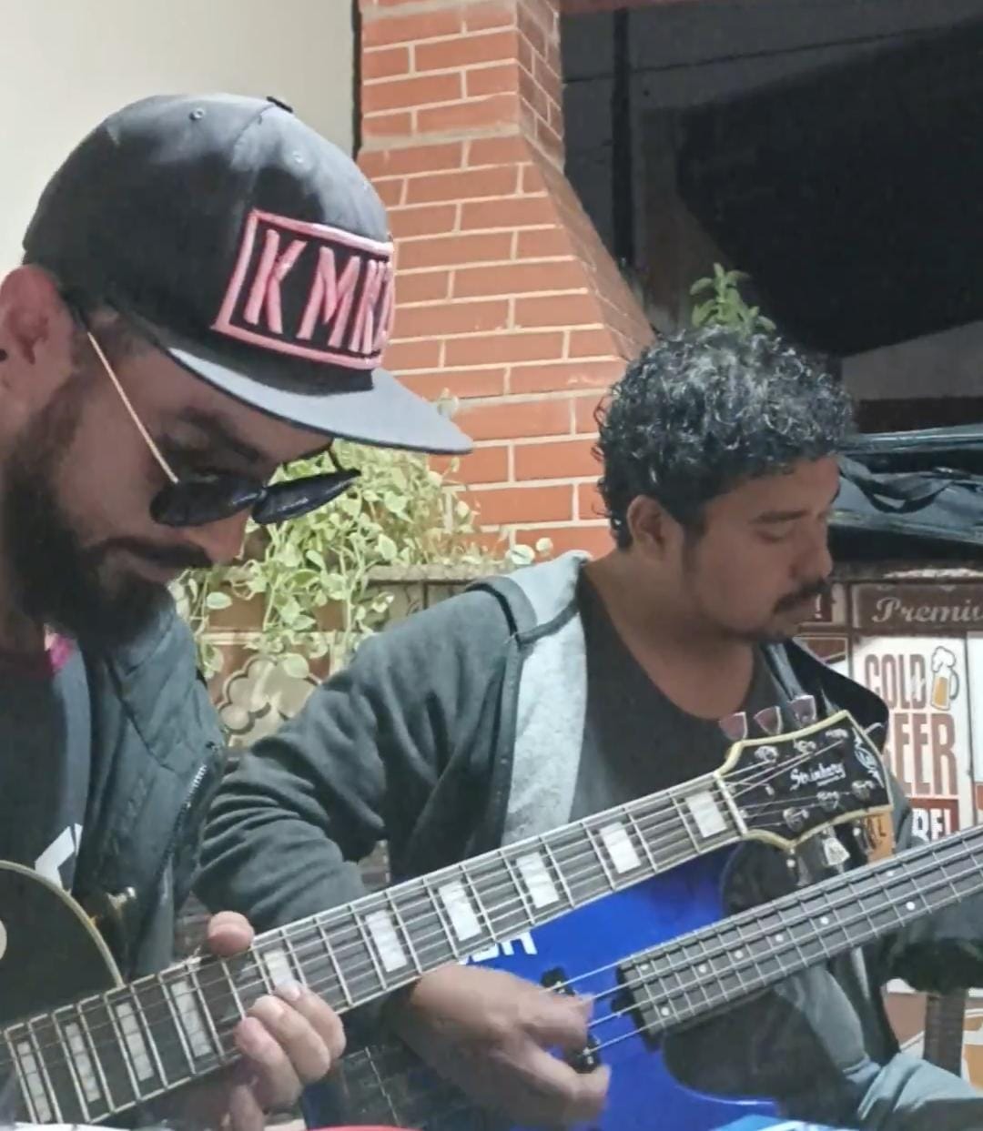Dois músicos tocando guitarra e baixo em um encontro informal