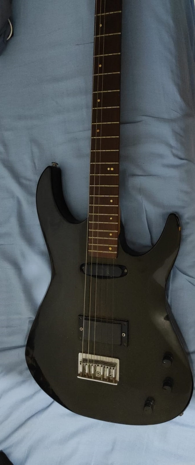 Guitarra preta desmontada, com o braço separado do corpo
