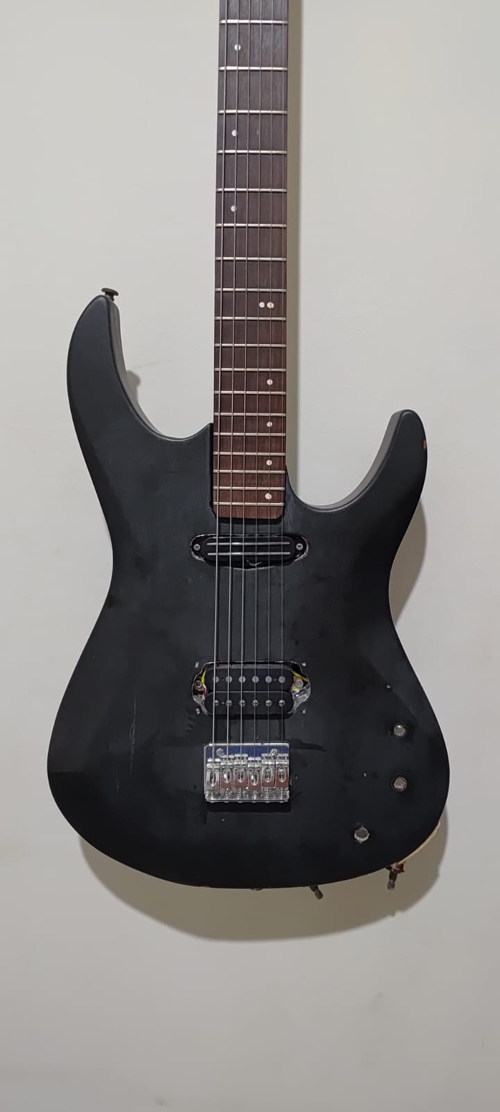 Guitarra preta pendurada com mini humbucker instalado na posição do braço