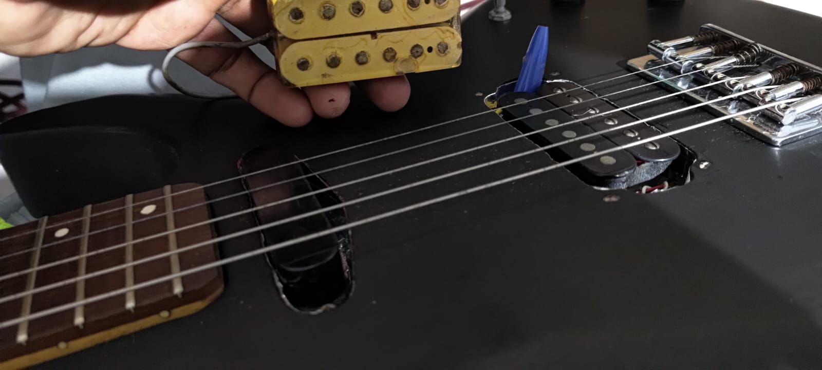 Captador claro removido acima da guitarra enquanto outro captador está instalado na ponte
