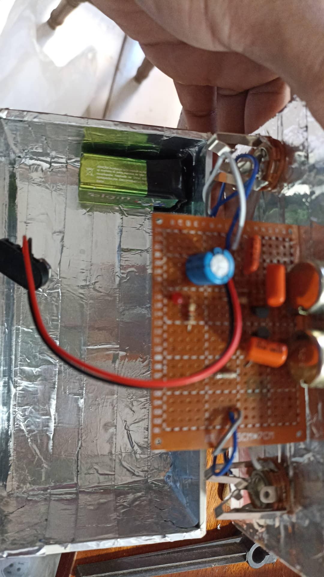 Interior da caixa do pedal com fita de alumínio, bateria, placa e cabeamento