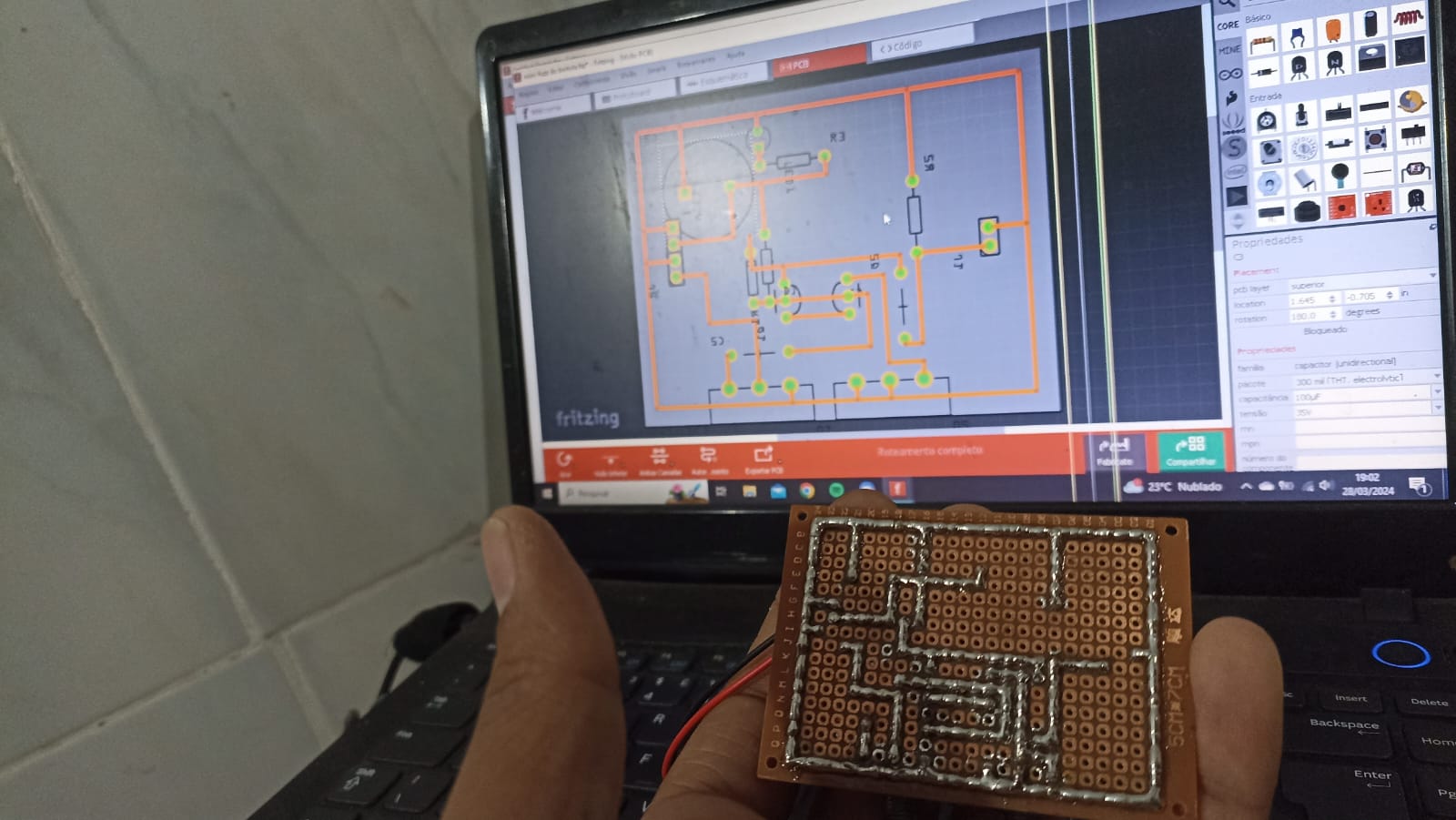 Placa universal soldada diante do desenho correspondente aberto no Fritzing
